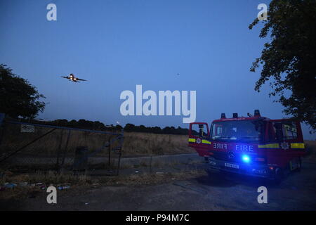 The London Fire Brigade battling a grass fire near Heathrow airport the size of four football pitches. Fifteen fire engines and 97 firefighters were deployed to tackle the blaze in Feltham, west London. Stock Photo