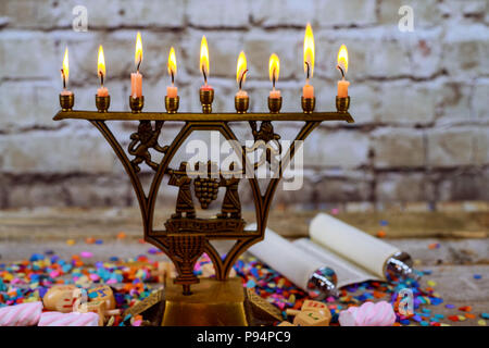 Bronze Hanukkah menorah with burning candles on wooden table front old vintage concrete wall Holiday concept. Stock Photo