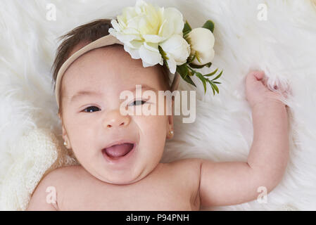 Portrait of smiling cute baby girl lay on soft white background Stock Photo