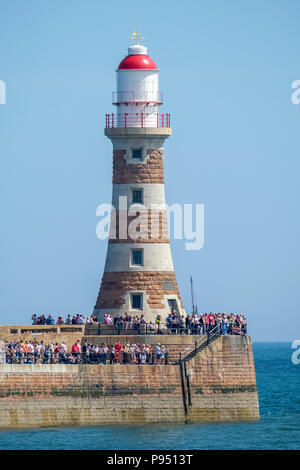 Sunderland, UK. 14th July 2018. Spectators sitting on Roker Lighthouse, enjoying the weather and watching the Tall Ships leave the Port of Sunderland.  The lighthouse was completed in 1903.  Its distinctive stripes are of naturally coloured red and white Aberdeen granite. When built it was said to be Britain's most powerful port lighthouse. It still functions today. Credit: Tim Withnall/Alamy Live News Stock Photo