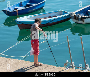 Lyme Regis, Dorset, UK. 15th July 2018.  UK Weather: A very hot and sunny St Swithin's Day in Lyme Regis. A boy with fishing rod.  The scorching hot temperatures are set to contune with temperatures reaching 30 degrees in many parts of the UK again today as the heatwave continues. Credit: PQ/Alamy Live News. Stock Photo