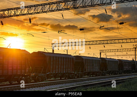 railroad infrastructure during beautiful sunset and colorful sky, railcar for dry cargo, transportation and industrial concept Stock Photo