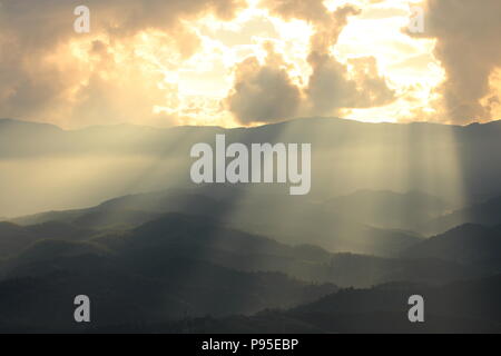 Dramatic god lights passing through clouds and shining on mountain ranges. warm light shower. God hope and dream concept Stock Photo