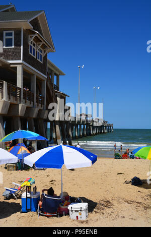 Tourists lay-out on the beach next to Jennette's Pier in Nags Head on the Outer Banks of North Carolina Stock Photo