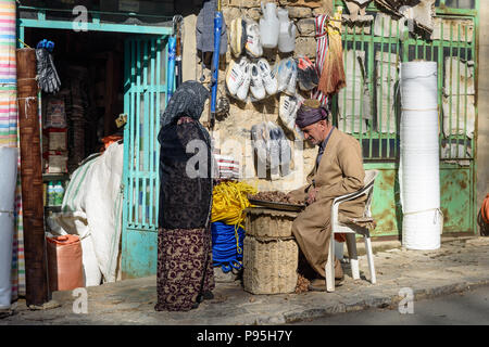 Howraman, Kurdistan Province, Iran - April 5, 2018: Kurdish man cleans and crack walnuts on the street near shop in Howraman village or Uraman Takht i Stock Photo