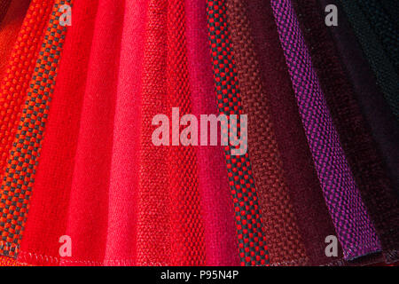 Colourful red fabrics in different colour tone stack in layers on display. Stock Photo