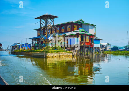 The primitive timber water tower next to the large house on stilts in village on Inle Lake, Inpawkhon, Myanmar. Stock Photo