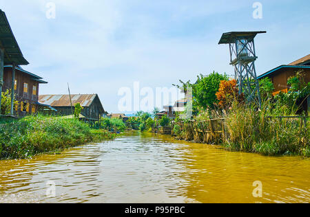 The water street with row of old houses hidden behind the lush greenery, Inle Lake, Myanmar. Stock Photo