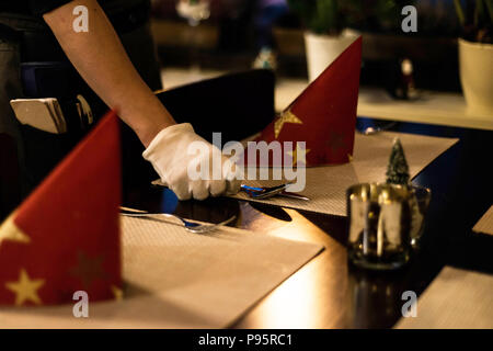 Hand placing dishes on Christmas New Year Holiday Table Setting Dinner Decorations. Decor Stock Photo