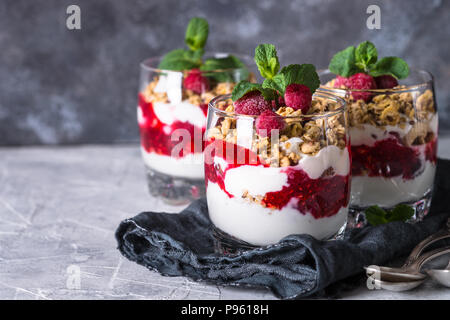 Healthy layered dessert with yogurt, granola, jam and raspberries in glass. Stock Photo