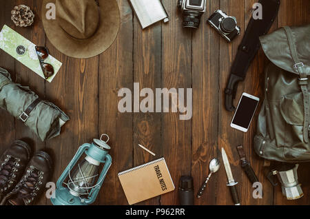 Hiking gear frame including machete, knife, clothes, boots, lantern, camera, hat, map, compass, mobile phone. Wanderlust, safari postcard, poster. Stock Photo