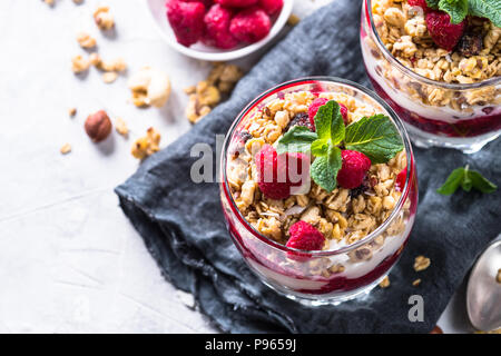 Healthy layered dessert with yogurt, granola, jam and raspberries in glass. Stock Photo