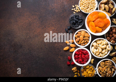 Assortment of nuts and dried fruits in bowls. Cashew, hazelnuts, walnuts, almonds, brazilian nuts, raisins, dried apricots, cherry and pine nuts. Top  Stock Photo