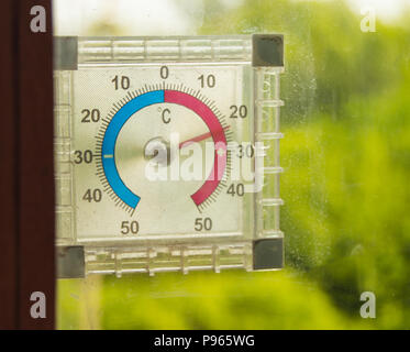 https://l450v.alamy.com/450v/p965wg/street-thermometer-hanging-on-the-window-and-shows-the-temperature-of-the-air-in-the-summer-against-the-green-trees-p965wg.jpg