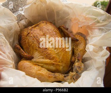 grilled whole chicken with crispy Golden skin on white parchment, top view, close-up. Stock Photo