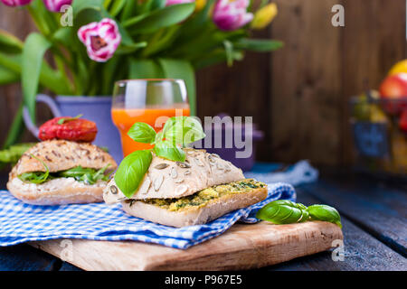 Sandwiches with fresh Italian rolls with avocado, basil, tomatoes and soft cheese. Breakfast healthy eating on a dark background. Free place for text or postcard. Stock Photo