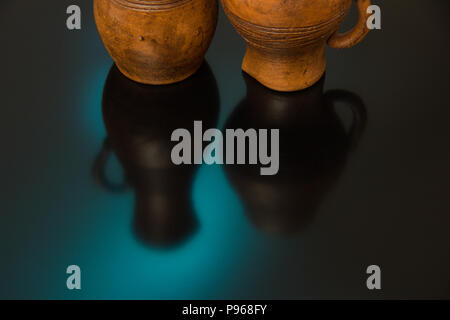 Ceramic pots with carved pattern on a black background with blue and yellow light Stock Photo