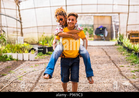 young beautiful teenager play with his mother middle age pretty woman carrying her to his back. couple mother son having fun together like a perfect f Stock Photo