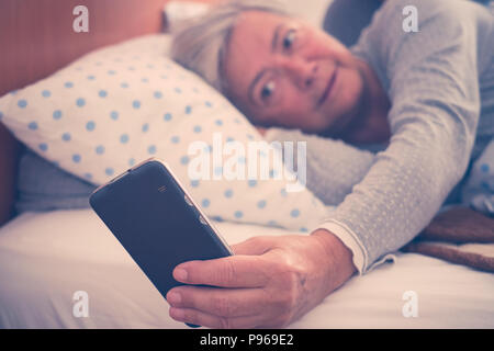 nice beautiful couple enjoy the morning and check the alarm on the phone. app help to wake up and start the day and the usual life. bedroom and bed pl Stock Photo
