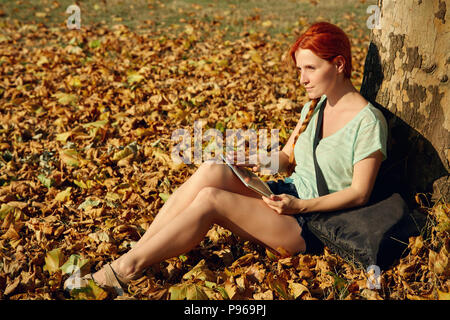 woman sitting under a tree in park Stock Photo