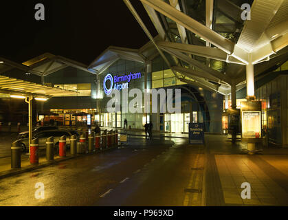 Exterior view of the terminal building at Birmingham International Airport at night with an illuminated sign of the airport's name Stock Photo