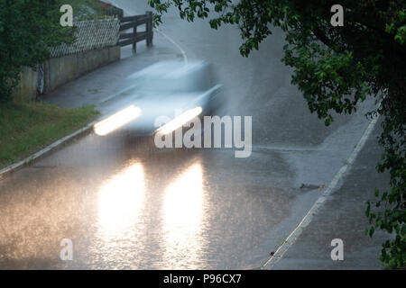 Car driving the street down in the rain Stock Photo