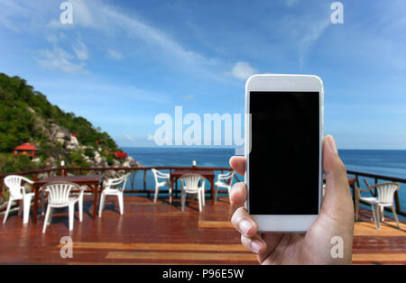 Man's hand shows mobile smartphone in vertical position, blurred background - mockup template Stock Photo