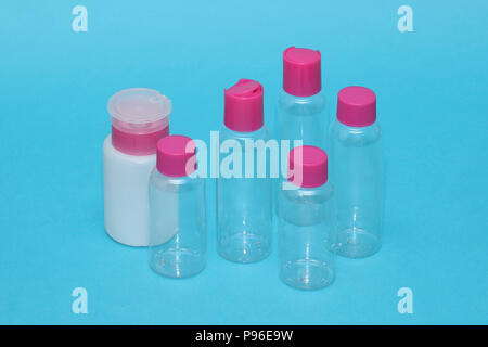 Empty toiletries travel bottles with pink lid on blue background Stock Photo
