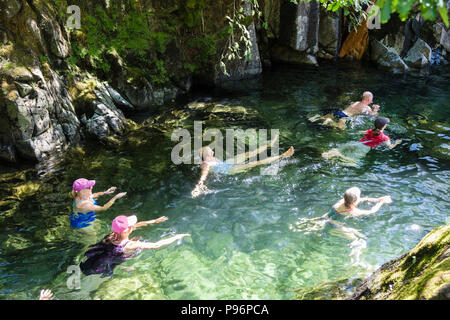 People wild swimming in a rocky pool in Langstrath Beck on a hot summer's day. Stonethwaite Borrowdale Lake District National Park Cumbria England UK Stock Photo