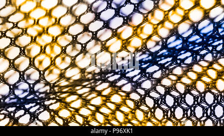 Abstract texture of net with hexagonal cells. Artistic detail of the decorative netting in black, yellow and blue color on white background. Stock Photo