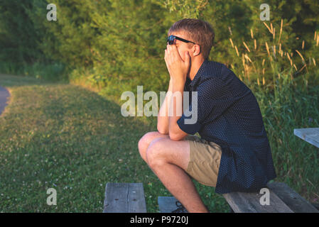 Upset teenager sitting on bleachers. Stock Photo