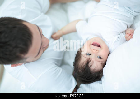 Smiling father with his  baby son hugging in bed Stock Photo