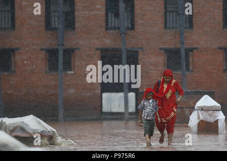 Kathmandu, Nepal. 15th July, 2018. A mother and child cover themselves with a shawl during a brief rainfall in Kathmandu, Nepal on Sunday, July 15, 2018. Credit: Skanda Gautam/ZUMA Wire/Alamy Live News Stock Photo