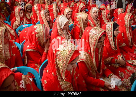 Srinagar, India. 15th July 2018. Kashmiri Muslim brides sit for a mass marriage event in Srinagar, Indian controlled Kashmir on Sunday. Mass wedding of 105 Muslim couples held in Srinagar organised by social welfare organisation primarily to help the economically backward families who cannot afford the high costs of the ceremony, dowry and expensive gifts, that still prevails in many communities of India. Credit: SOPA Images Limited/Alamy Live News Stock Photo