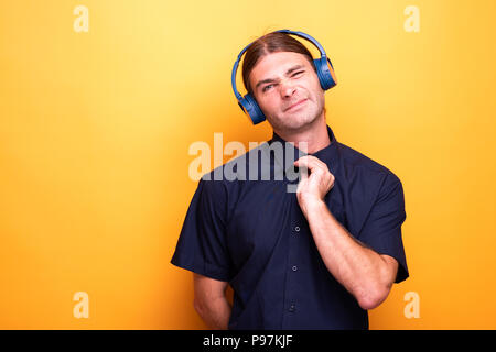 Man arranging his shirt while wearing headphones Stock Photo