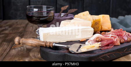 Assorted cheese, meat, wine in a glass and olives. A delicious Italian snack for a party. Copy space Stock Photo