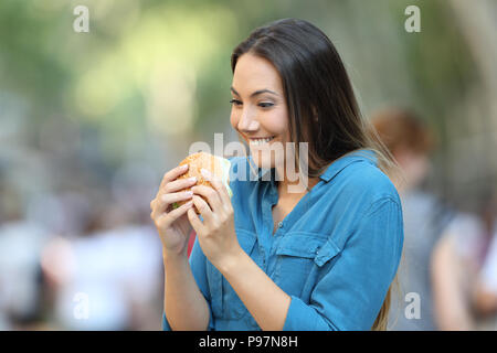 Excited woman ready to eat a burger on the street Stock Photo