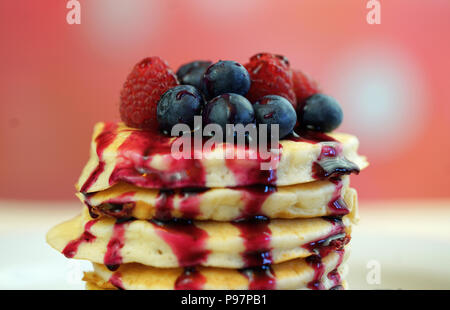 Stack of pancakes with raspberries, blueberries and drizzled with blueberry maple syrup, macro closeup. Stock Photo