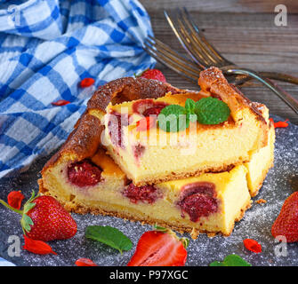изображения:pieces of cheesecake with strawberries on a black graphite plate, close up Stock Photo