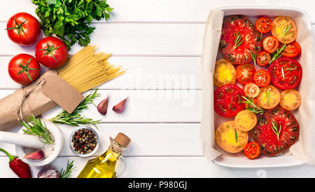 Fresh organic ingridients, pasta spaghetti of italian recipes. Tomatoes with rosemary into ceramic. Healthy food concept on white wooden table backgro Stock Photo