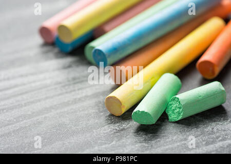 Row Pile of Multicolored Chalks Crayons on Dark Scratched Blackboard. Back to School Business Creativity Graphic Design Crafts Kids Concept. Poster Ba Stock Photo