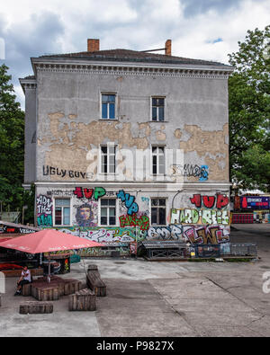 Berlin, Friedrichshain, RAW Gelände. Weathered old Ambulatarium building, colourful street art & fast food stall with outdoor seating Stock Photo