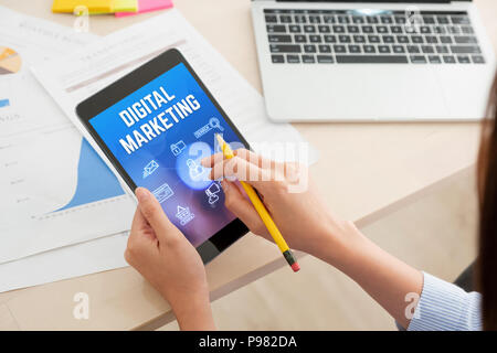 Shoulder view of woman use tablet with digital marketing feature online on table at office.Digital business concept Stock Photo