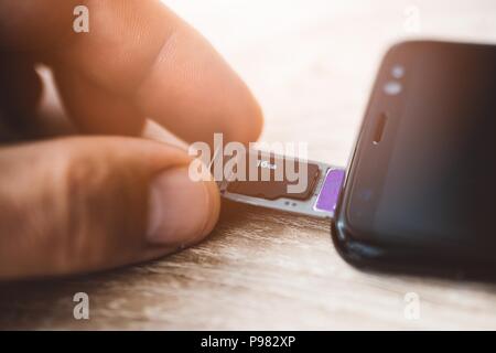 Man inserting memory card and sim card to smartphone Stock Photo