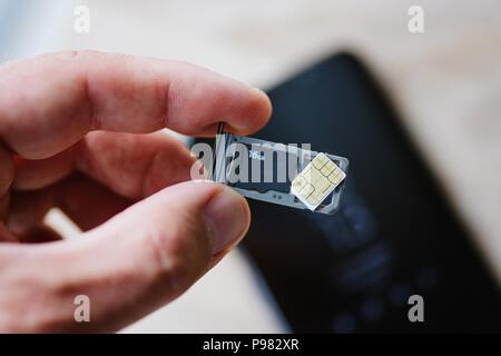 Man inserting memory card and sim card to smartphone Stock Photo
