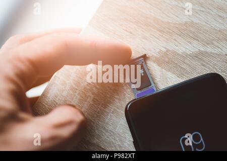 Man inserting memory card and sim card to smartphone Stock Photo