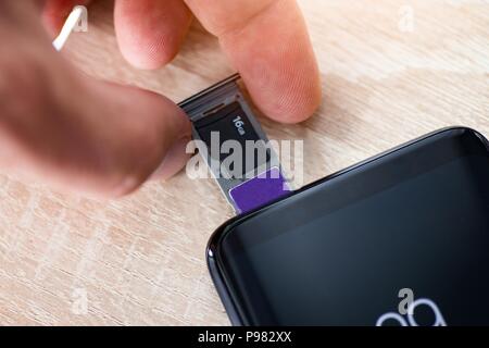 Man inserting memory card and sim card to smartphone Stock Photo