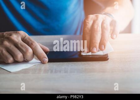 Man cleaning smartphone screen with cloth before applying protective cover foil Stock Photo