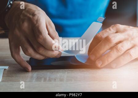 Man applying protective screen foil on his smartphone touchscreen Stock Photo