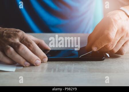 Man applying protective screen foil on his smartphone touchscreen Stock Photo